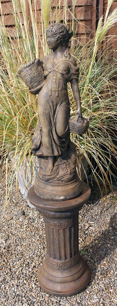 Stone statue of a young boy holding a bird bath in a country